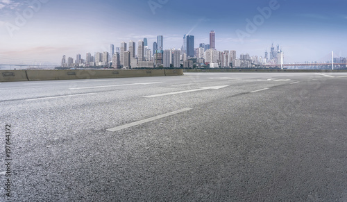 The empty asphalt road is along the modern commercial building in the Chinese city