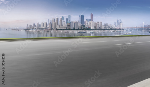 The empty asphalt road is along the modern commercial building in the Chinese city