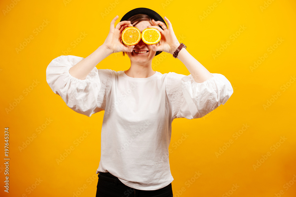 Cheerful woman holding two oranges on her eyes Cheerful woman holding two oranges on her eyes