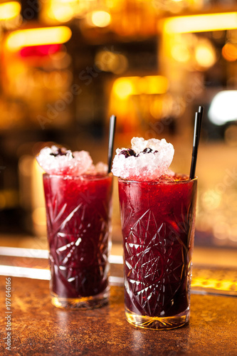 Two colorful red blueberry cocktails in bar
