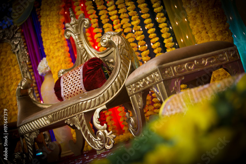 Indian dessi wedding stage decorated with yellow color  flowers and golden color  seats  photo