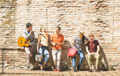 Group of happy excited friends having fun outdoor cheering with guitar - Young people enjoying spring summer time together at city town tour - Youth friendship concept on warm afternoon color filter