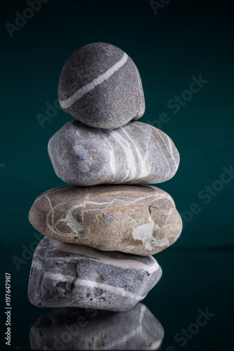 Stein Meditation vier Steine gestapelt mitte grüner Hintergrund vertikal als Achtsamkeitsübung und innerer Balance photo