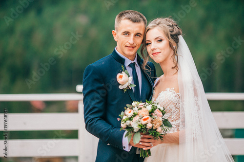 bride and groom in carpathians, mountains, beautiful nature, landscape, scenery. Newlyweds at mountain terrace. Windy veil. Tender picture. photo