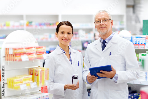 medicine, healthcare and technology concept - apothecaries with tablet pc computer and medication at pharmacy