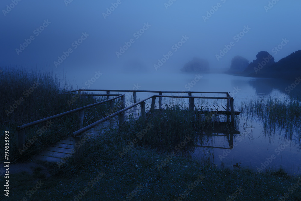Naklejka premium mysterious wooden jetty on lake at night