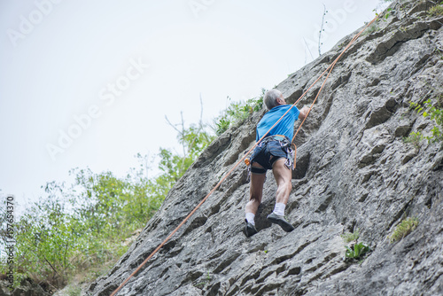 Male climber with safety equipment learning to climb in the mountains at Cheile Turzii in Romania. Hot, sunny summer day in the nature