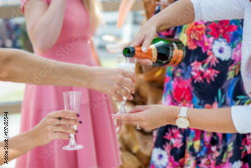 Group of girls in pink dress code celebrating - pouring champagne in glasses and drinking. Cheerful bride and bridesmaids party before wedding. Women having fun