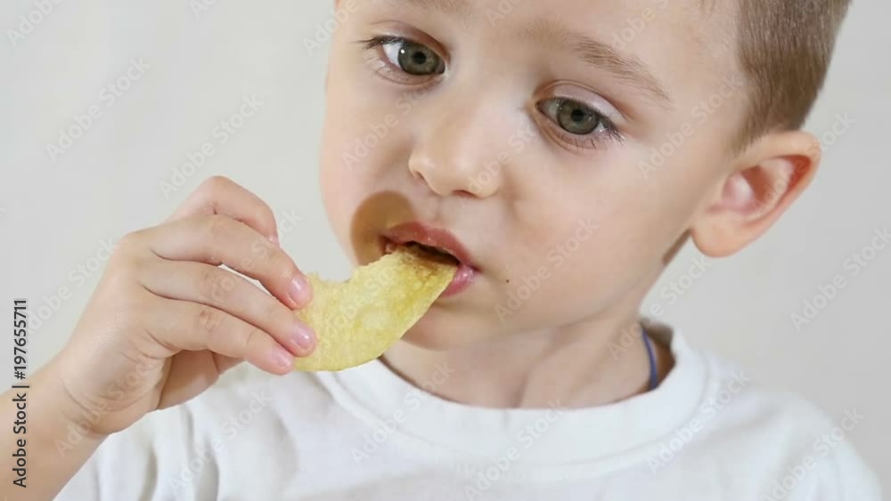 A little boy in slow motion eating potato chips, close-up A little boy in slow motion eating potato chips, close-up