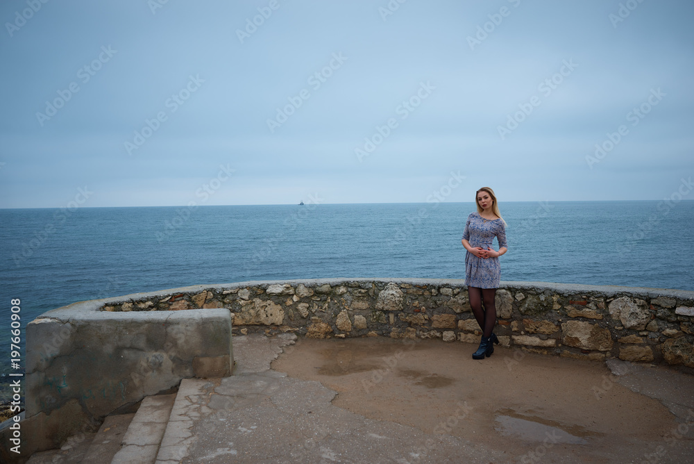 Young hot sexy woman in a short  dress walking near the sea