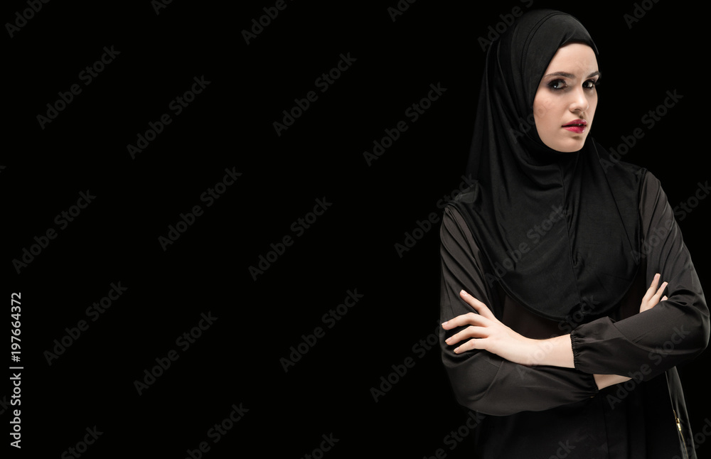 Portrait of woman in hijab standing against black background