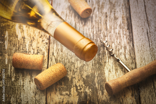 Glass bottle of wine with corkscrew on wooden table background