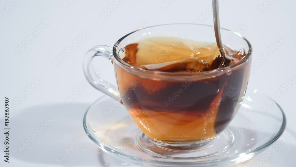 Man stirring tea with spoon in glass cup Man stirring tea with spoon in glass cup