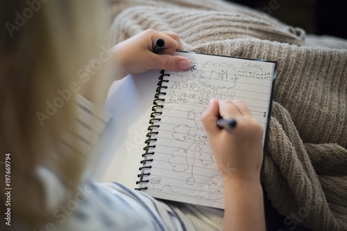High angle view of girl writing in diary while sitting at home