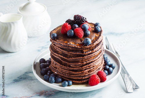 a stack of chocolate gluten free pancake with fresh berries. morning healthy breakfast