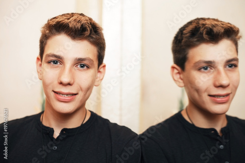 The guy with braces on his teeth stands near the large mirror in the restaurant