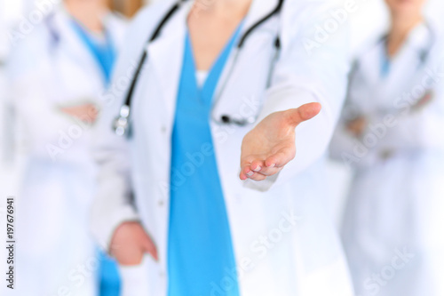 Group of medicine doctors offering helping hand  for shaking hand or saving life closeup. Partnership and trust concept in health care or medical cure 