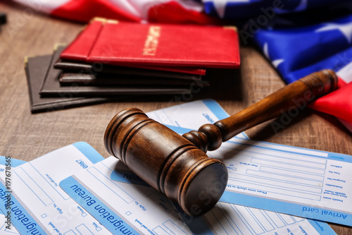 Gavel, arrival cards, passports and American flag on table. Legal immigration