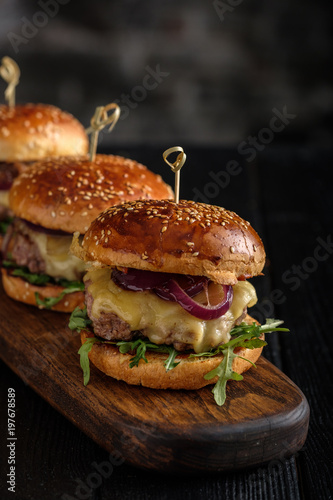 Homemade juicy burgers with beef, cheese and caramelized onions on the wooden table. Street food, fast food