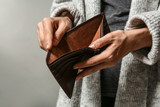 Poor woman showing her empty purse on grey background