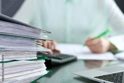 Bookkeeper or financial inspector making report, calculating or checking balance. Binders with papers closeup. Audit and tax service concept. Green colored image background 