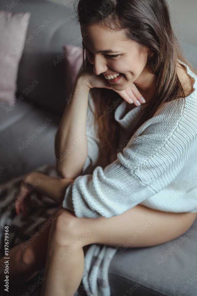 Sexy girl laughing while sitting on a couch Sexy girl laughing while sitting on a couch