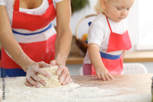 Mother and her cute daughter hands prepares the dough on wooden table. Homemade pastry for bread or pizza. Bakery background