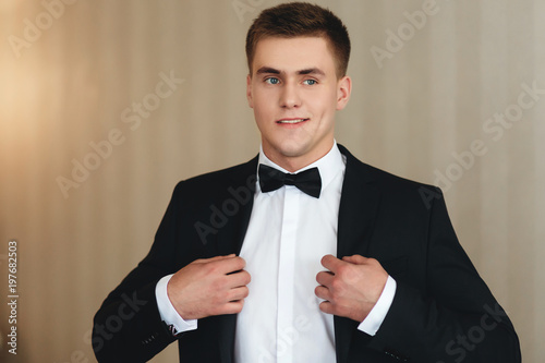 A man dresses a classic black suit and a bow tie