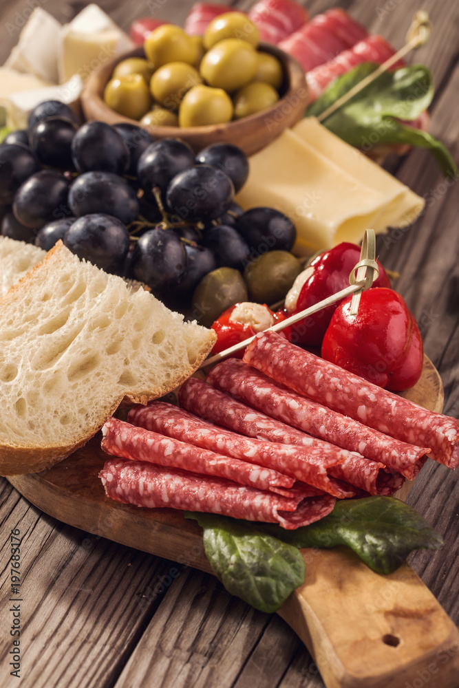 Antipasti snacks on wooden platter closeup shot Antipasti snacks on wooden platter closeup shot