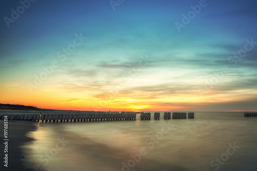 Sunrise, sunset of a beautiful winter landscape with frozen wooden breakwater. Concept holidays and travel