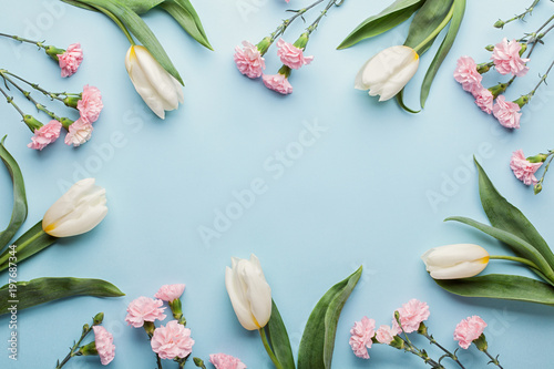 Frame made of white tulip flowers on blue background. Flat lay, top view. Minimal floral mock up concept.