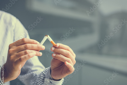 Stop smoking concept. Close-up of man breaking cigarette in half.