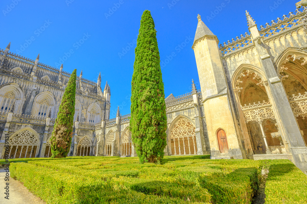 Portugal, Batalha. Courtyard of Batalha Monastery or Saint Mary of the Victory Unesco Heritage and one of the best examples of Gothic architecture in Portugal, mixed with Manueline style. Blue sky.