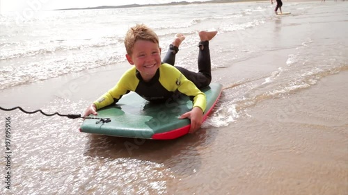 Little boy having fun at the beach, being pulled along on a bodyboard. photo