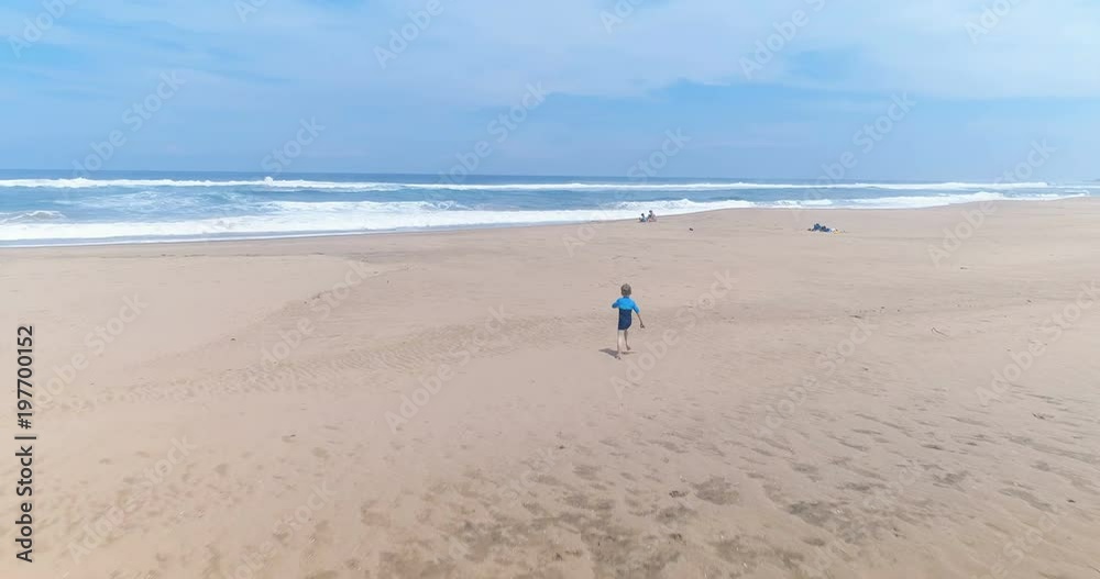 Cute little boy running towards mother and brother near ocean edge on beach smooth dolly Cute little boy running towards mother and brother near ocean edge on beach smooth dolly