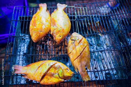 Grilled fish is used on the charcoal grill, a popular food at the evening market in Thailand. photo