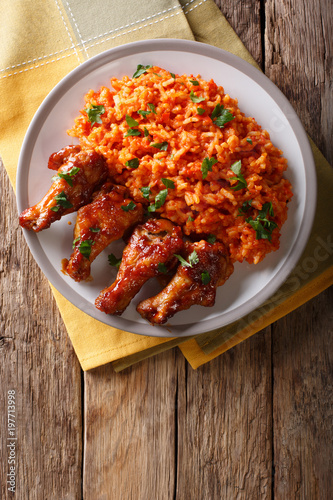 Nigerian food party: Jollof rice with fried chicken wings close-up. Vertical top view