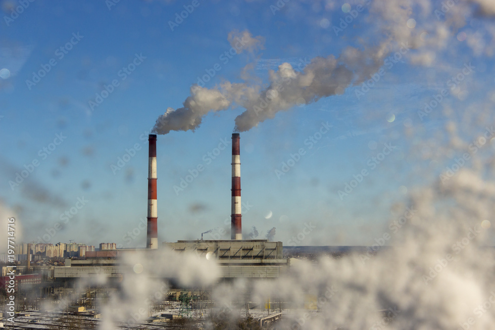 View from the window to the factory, pipes emitting harmful substances into the atmosphere. Defocused.
