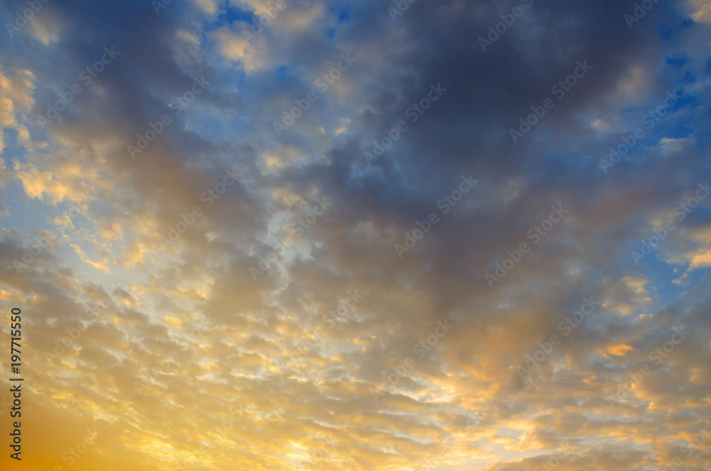 Beautiful colorful sunset sky background with the light of sun behind.Blue and purple dramatic clouds. 