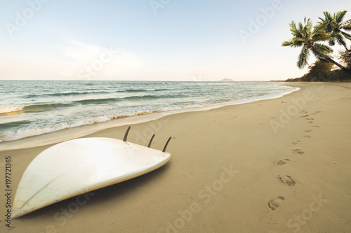Fototapeta Naklejka Na Ścianę i Meble -  Surfboard on tropical beach at sunrise in summer. seascape of summer beach with sea, blue sky background.
