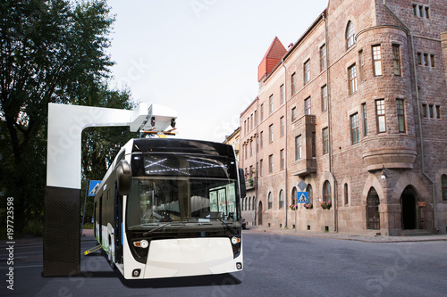 Electric bus at a stop is charged by pantograph