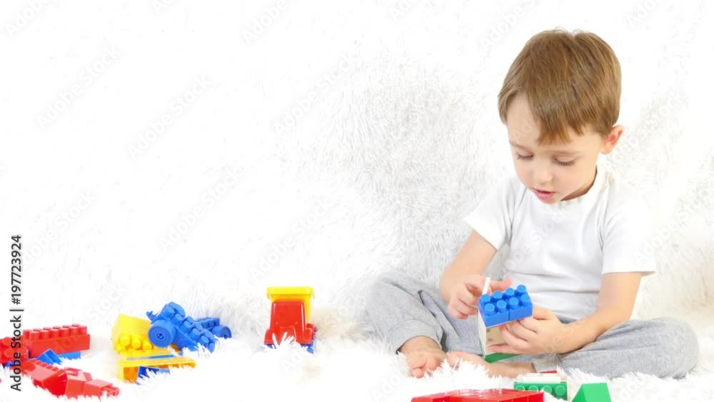 Happy toddler sitting on couch, playing in colored blocks, sitting on white background. Happy toddler sitting on couch, playing in colored blocks, sitting on white background.