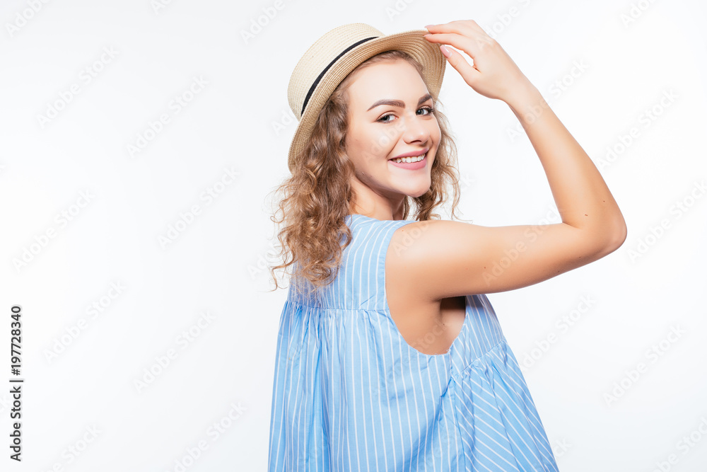 Portrait of a smiling attractive woman in summer dress and hat posing while standing and looking at camera isolated over white background
