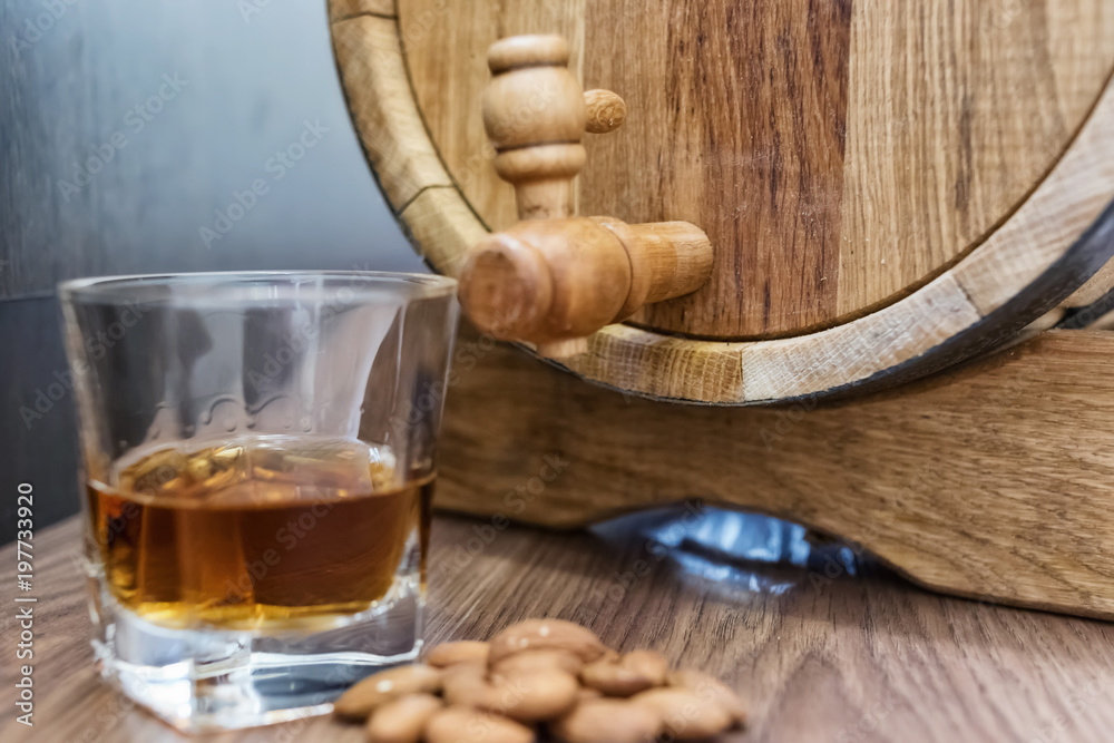 A small wooden oak barrel for home production and a stack of whiskey aged in it A small wooden oak barrel for home production and a stack of whiskey aged in it
