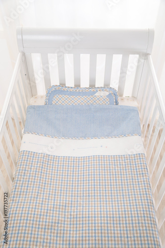 Cozy baby cot with white square pillows and patchwork comforter blanket with stars and black stripes photo