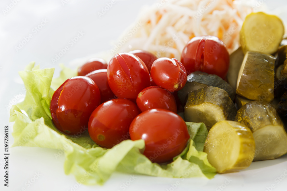 cold appetizer, pickles and tomatoes with sauerkraut laid out on lettuce leaves close-up cold appetizer, pickles and tomatoes with sauerkraut laid out on lettuce leaves close-up