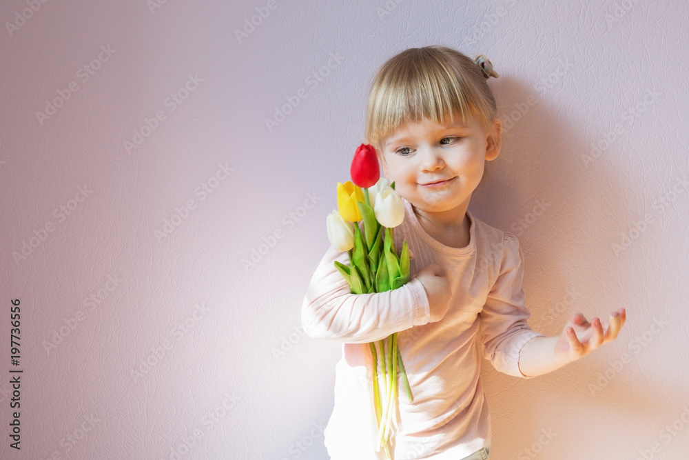Sweet happy little blond-haired girl holding a bouquet of colorful tulips in her hands. Shot 3/4. Copy space. Sweet happy little blond-haired girl holding a bouquet of colorful tulips in her hands. Shot 3/4. Copy space.