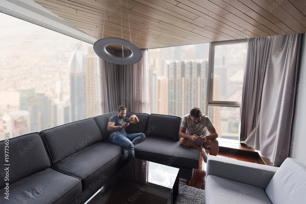 two young men using a mobile phones at home two young men using a mobile phones at home