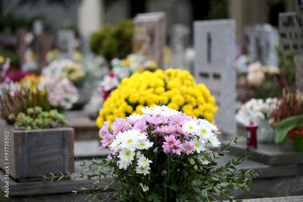 yellow and white flowers on the grave of a cemetery