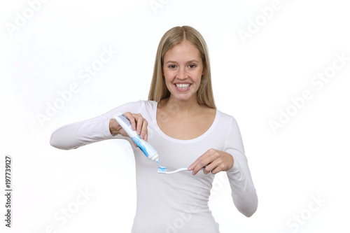 Hübsche blonde Frau drückt Zahnpasta auf eine Zahnbürste © Joerch